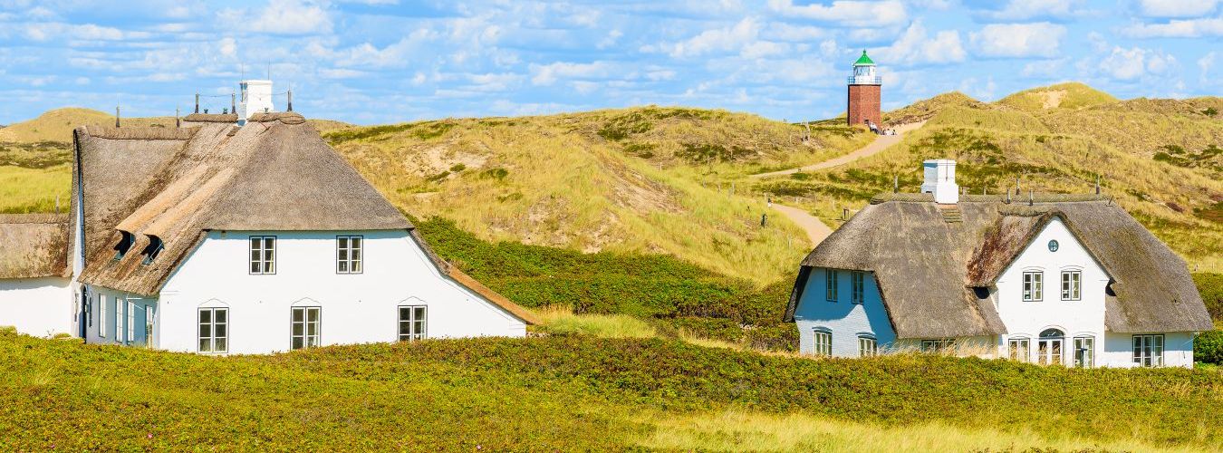 Deux maisons nordiques typiques devant un paysage vallonné et verdoyant